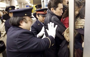 Station attendant pushing passengers into over-crowded trains. All in a morning's commute.